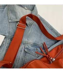 Détail de la large bandoulière réglable et boucle en métal argenté sur sac en toile orange