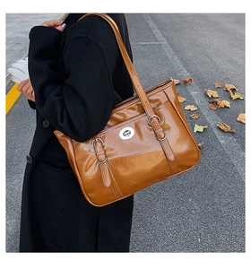 Brown oil wax leather tote bag featuring silver metal lock and strap buckles on street