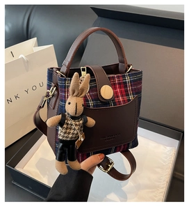 Detail of British plaid bucket bag with leather trim and cute rabbit doll keychain