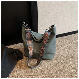 Detail of greyish-green suede bucket bag featuring ethnic bohemian wide shoulder strap