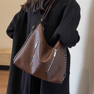 Large dark brown leather chain hobo shoulder bag styled on a model in a black coat
