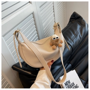 Detail of off-white lychee leather crescent bag with gold hardware and plush charm