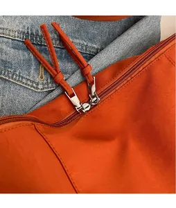 Détail du sac en toile orange avec double fermeture éclair et longues tirettes
