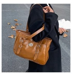 Detail of vintage brown leather tote bag with white contrast stitching and silver twist lock