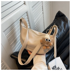Detail of off-white crescent crossbody bag in lychee texture PU leather with plush charm
