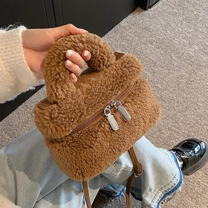 Braune Plüschhandtasche mit Griff und silbernen Reißverschlüssen in modischer Lifestyle-Ansicht
