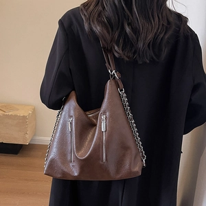 Large brown leather tote bag with chain strap and double zipper detail for travel
