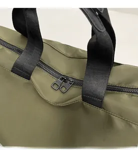 Detail of smooth double-way black zippers and reinforced webbing handles on army green bag