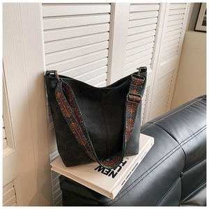 Detail of black suede hobo bag with ethnic style wide jacquard strap on book
