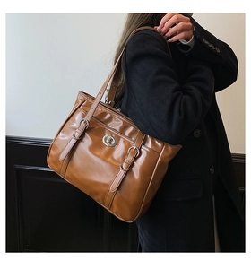 Detail shot of a brown vintage tote bag featuring a metallic twist lock and silver buckles