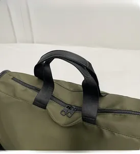 Detail view of reinforced leather handles and double zipper on olive nylon pillow bag