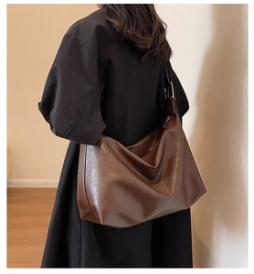 Detail of a large dark brown faux leather tote bag showing shiny texture and spacious design