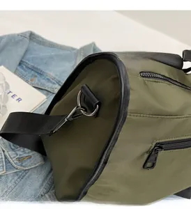 Close-up of olive green nylon bag showing polished metal hardware and leather trim