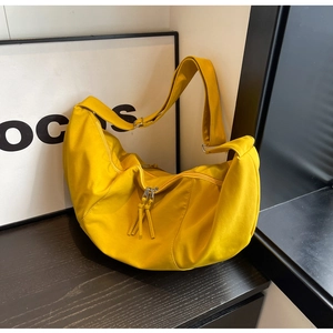 Détail du sac croissant jaune vif en toile avec double fermeture éclair sur bois