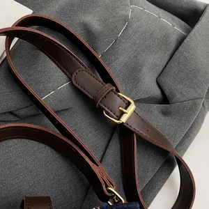Detail of adjustable dark brown leather shoulder strap with golden metal buckle for handbags