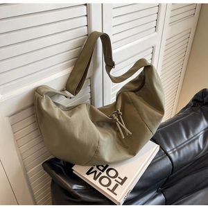 Gros plan d'un sac hobo vert olive avec bandoulière réglable sur volets blancs
