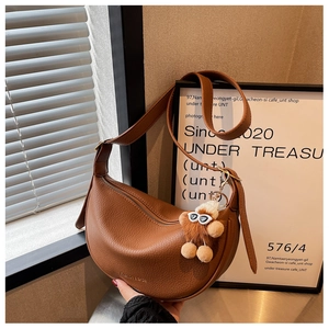 Close-up of brown litchi pattern leather hobo bag with cute plush pendant detail