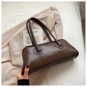 Detail of dark brown vintage leather shoulder bag resting on a beige textured blazer