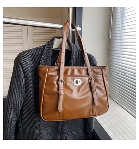 Detail of a brown textured leather tote bag with silver twist lock and shoulder straps