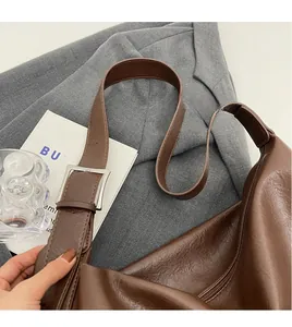 Detail of a brown vintage leather hobo bag with adjustable silver buckle and smooth long strap