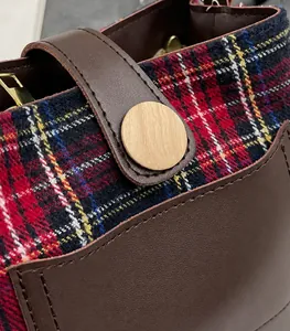 Detailed macro view of red and blue plaid wool fabric with premium brown leather trim