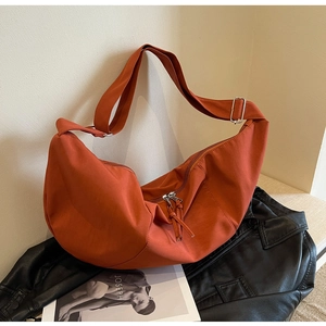Détail du sac demi-lune en toile orange avec bandoulière réglable sur veste en cuir