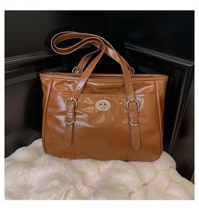 Close-up of brown polished oil-wax leather tote bag with silver metal buckles and hardware