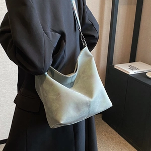 Retro grey-blue bucket bag with wide strap and topstitching shown on model side view