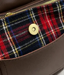 Close-up of golden magnetic buckle on vintage plaid wool and brown leather bucket bag