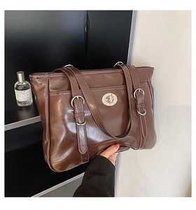 Detail of vintage brown tote bag featuring glossy texture and metallic twist lock closure