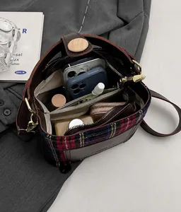 Detail view of plaid shoulder bag showing interior space with phone storage and wood button