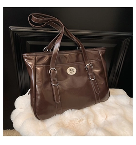 Detail of a dark brown oil wax leather tote bag featuring a silver twist lock and strap