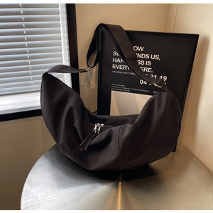 Détail du sac bandoulière en croissant noir avec double fermeture éclair et boucle métal