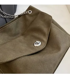 Close-up of the silver metal rotary lock and textured olive green leather of the bag