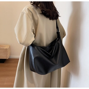 Model wearing a large black vintage hobo bag with adjustable silver buckle on a trench coat