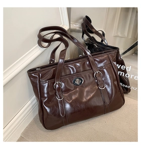 Detailed macro view of dark brown glossy patent leather tote with silver buckle and clasp