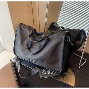 Close-up of black nylon large capacity pillow bag with durable handles and logo tag