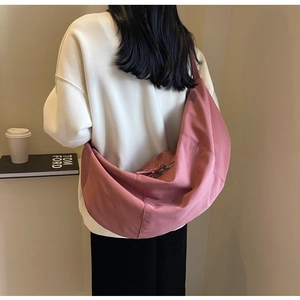 Détail du grand sac croissant en toile rose à l'épaule montrant le volume et le drapé