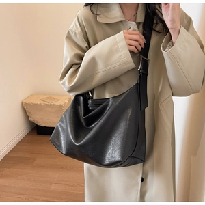 Detail of minimalist black leather hobo bag with adjustable silver buckle on a wide strap