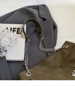 Detail of dark green leather shoulder bag featuring a silver chain and leather strap design