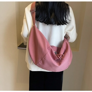 Détail du sac croissant en toile rose poudré avec bandoulière réglable et boucle métallique