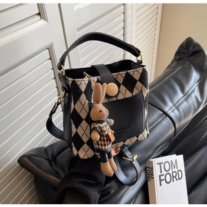 Close-up of beige quilted bucket bag with leather pocket and cute rabbit charm