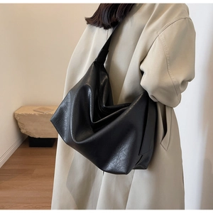 Detail of minimalist black large tote bag with textured PU leather shown on a model