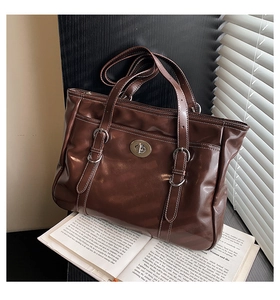 Detailed close-up of dark brown wax leather tote bag with silver buckle and hardware