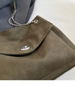 Close-up of olive green tote bag featuring textured leather and silver twist lock detail