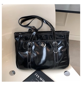 Detail of glossy black tote bag with white contrast stitching and silver twist-lock