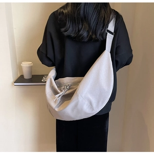 Détail de la bandoulière large réglable et du double zip en métal sur le sac en toile