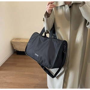 Close-up of black nylon travel bag with Come Knoc logo and adjustable shoulder strap