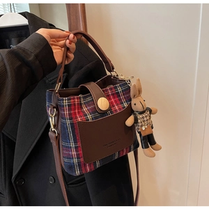 Detail of vintage plaid bucket bag with brown leather pocket and a cute rabbit charm
