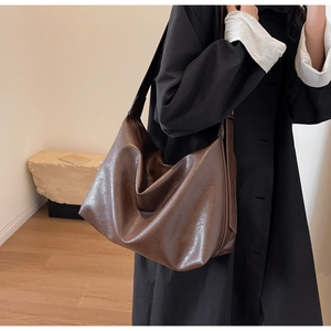 Detailed close-up of a large brown tote bag showing oily leather texture and soft structure